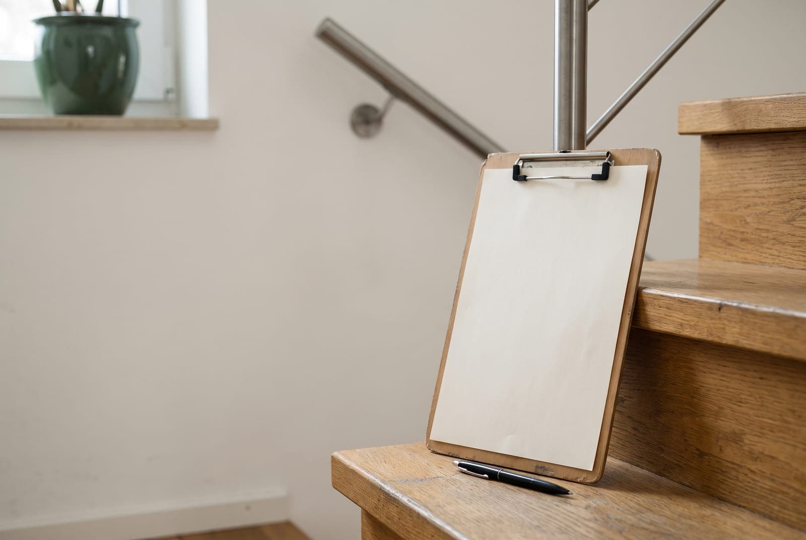 Klemmbrett mit leerem Blatt und Stift auf der untersten Stufe einer Holztreppe